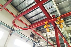  A red monorail overhead crane system with a yellow hoist and hook