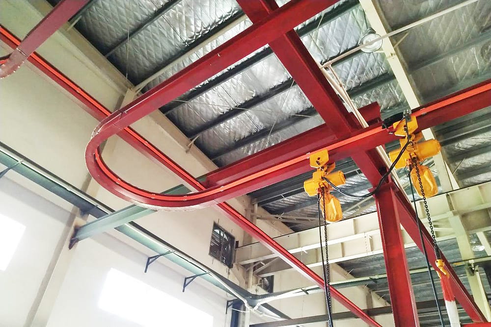 A red monorail overhead crane system with a yellow hoist and hook